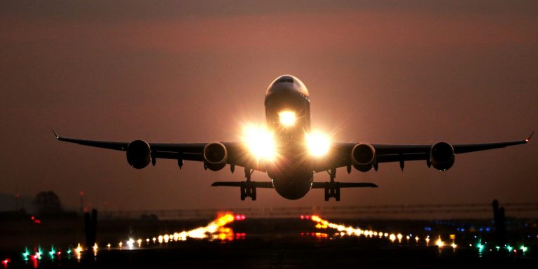 Aircraft taking off at night over the runway lights